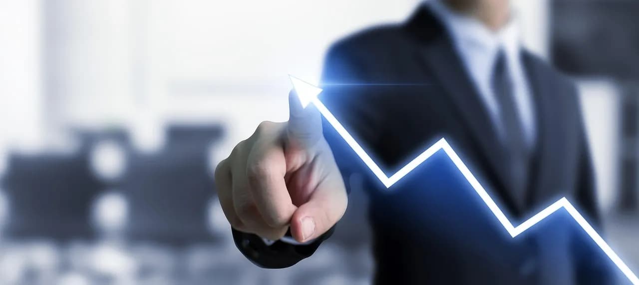 A hand pointing at a falling line on a business chart